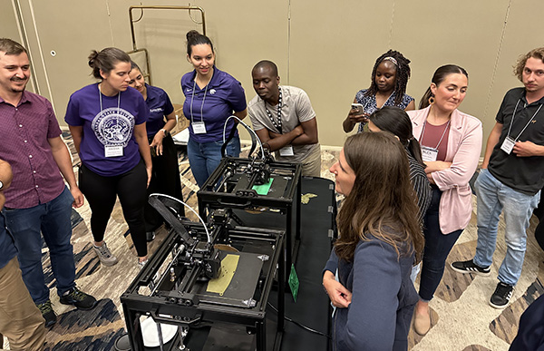 People gathered around 3d printing machine demonstration