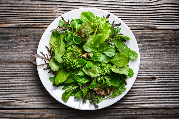 Green lettuce salad on a white plate ready for eating.