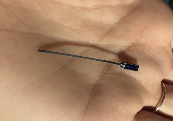 Solar-powered, butterfly radio telemetry transmitter held in a hand to show tiny size.