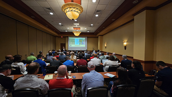 A room full of people facing the speaker and a slide about red crown rot.
